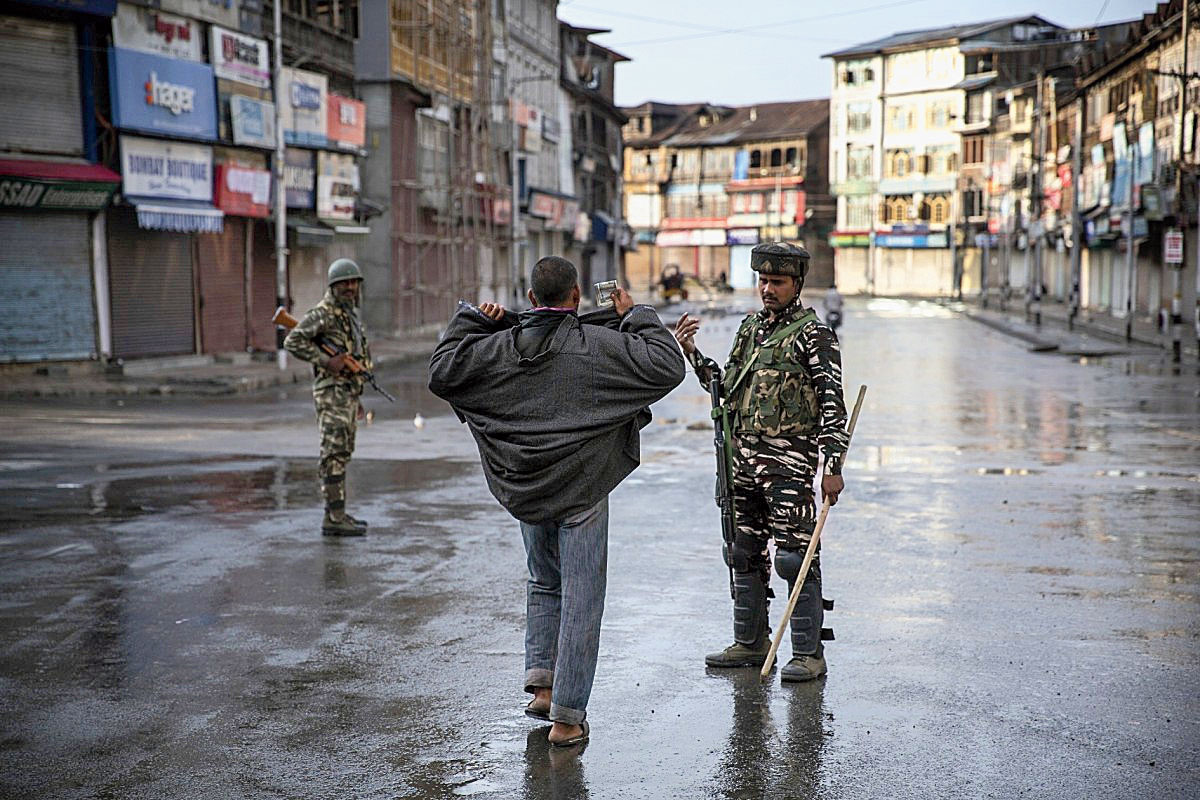 A paramilitary soldier orders a Kashmiri to open his jacket before frisking him during curfew in Srinagar on August 8, 2019.