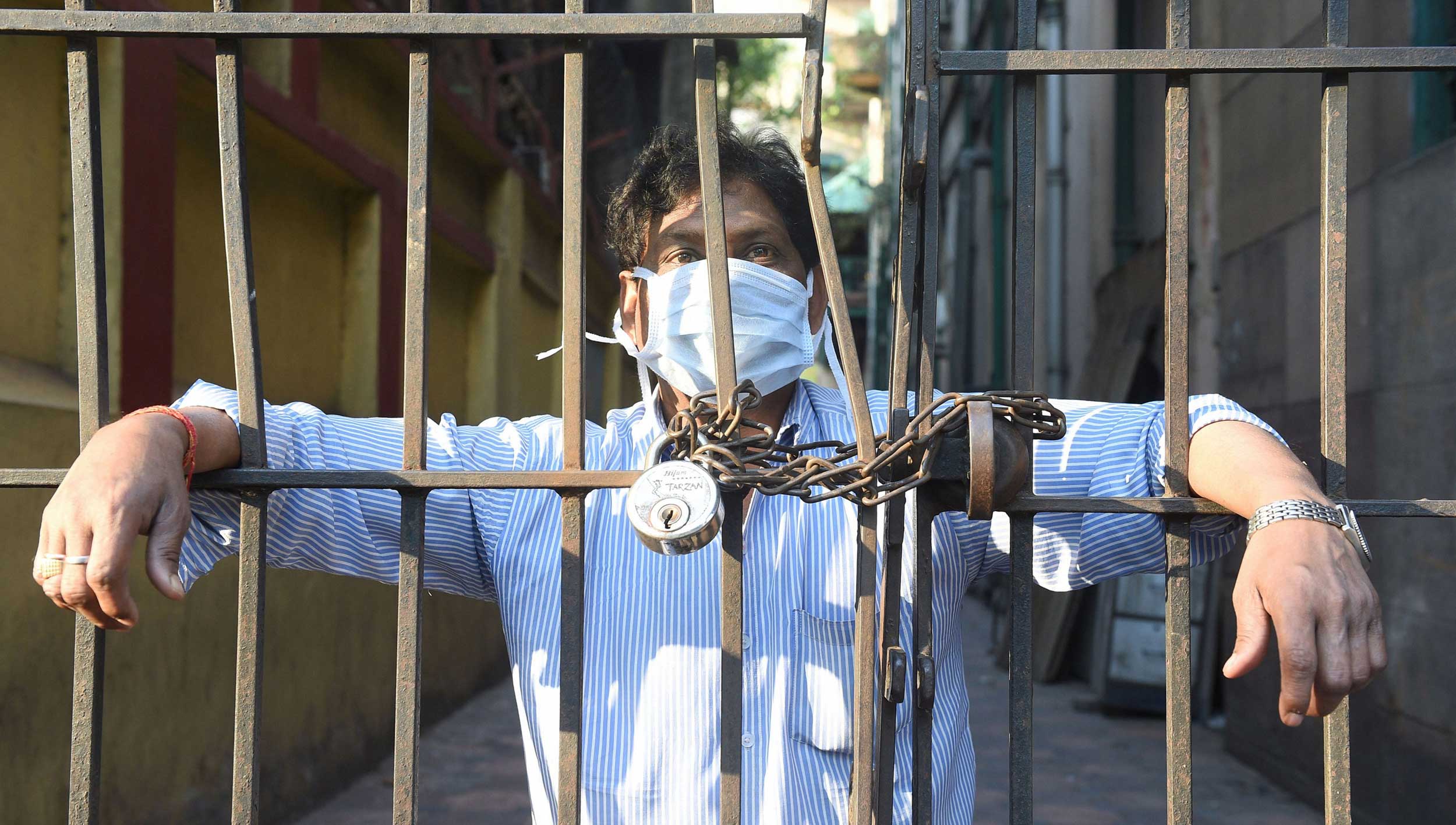 A man, wearing a mask, looks from a closed gate during coronavirus lockdown in Calcutta on Tuesday.