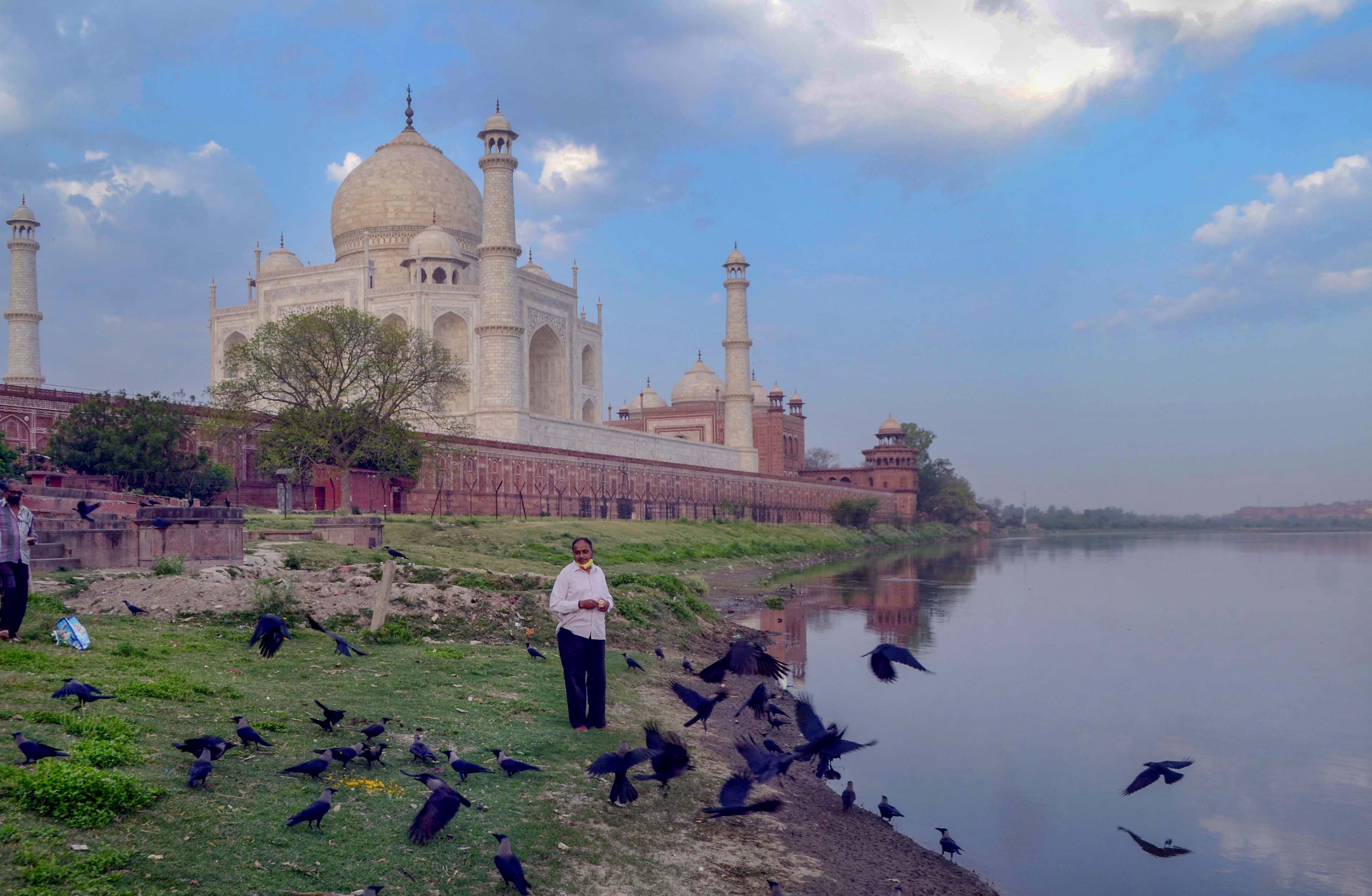 A man feeds birds on the banks of River Yamuna, during a nationwide lockdown to curb the spread of coronavirus, near the historic Taj Mahal in Agra, Wednesday, April 8, 2020