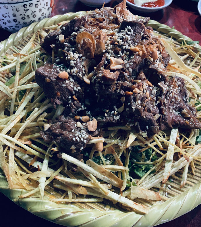 Beef cooked with sesame seeds is served on a bed of fried yam where the soft texture of the meat is complemented by the crunch of yam