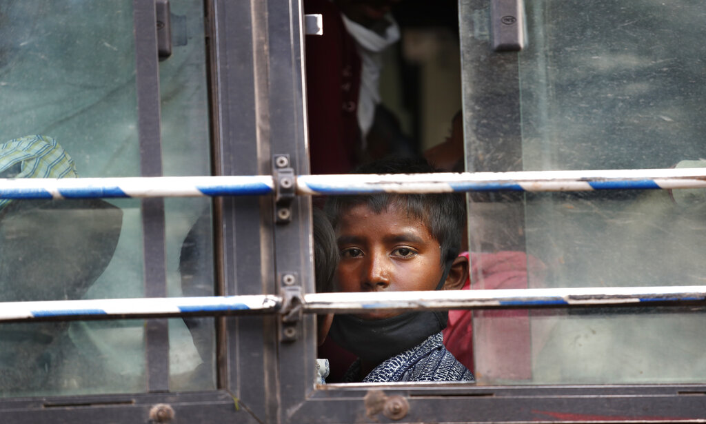 The son of a migrant daily wage laborer looks out a bus window bus as he travels to his hometown following a lockdown amid concern over spread of coronavirus in New Delhi, on Friday, March 27, 2020.