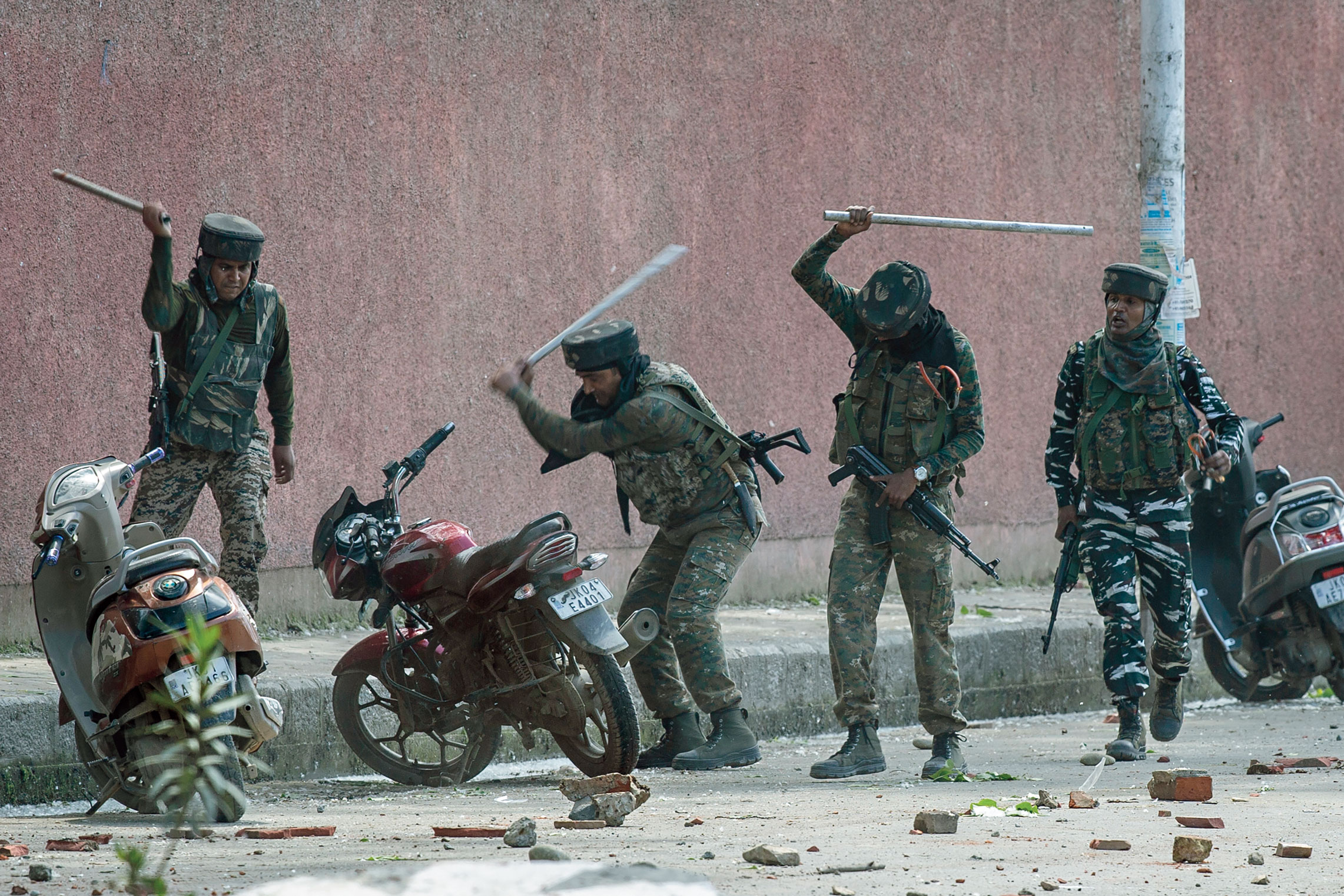 Security forces break motorbikes parked outside a college in Srinagar on May 14, 2019, as students protested against the alleged rape of a child.