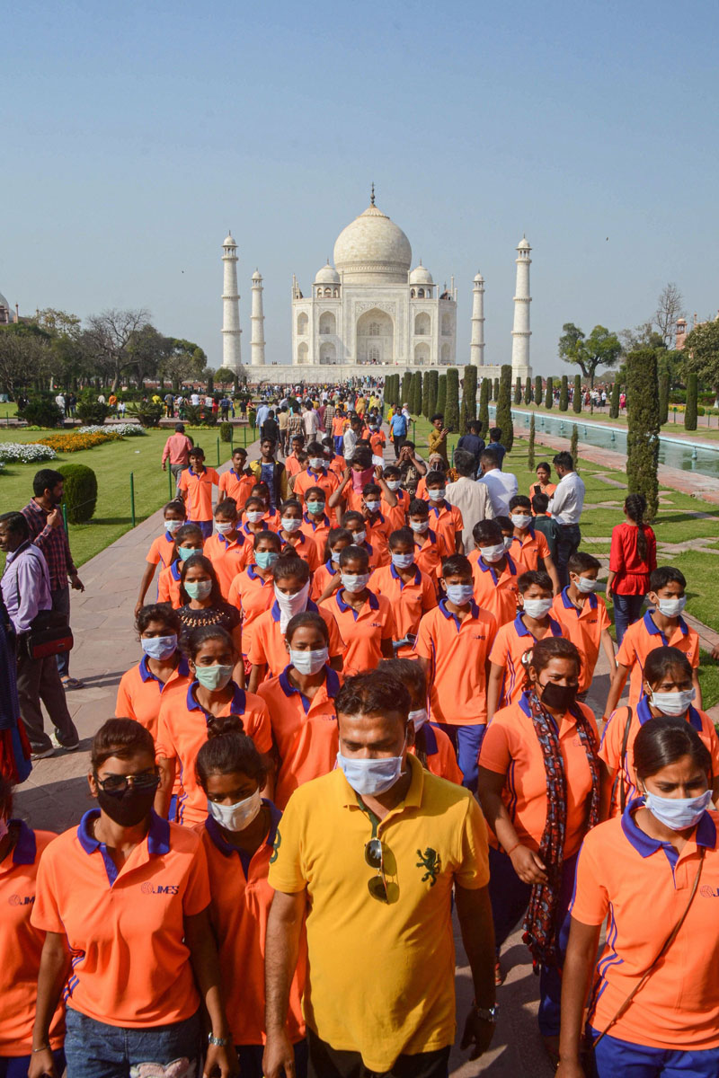 Tourists wear masks as a preventive measure against coronavirus during their visit to the Taj Mahal in Agra on Wednesday