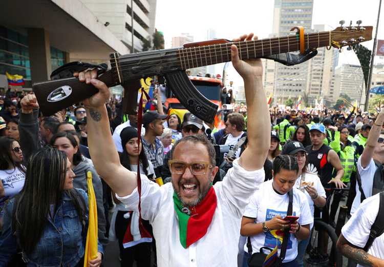 A Colombian musician holds up his 'escopetarra', a guitar that incorporates an assault rifle as a symbol of peace, during a musical protest against the government of President Ivan Duque in Bogota, Colombia, on December 8