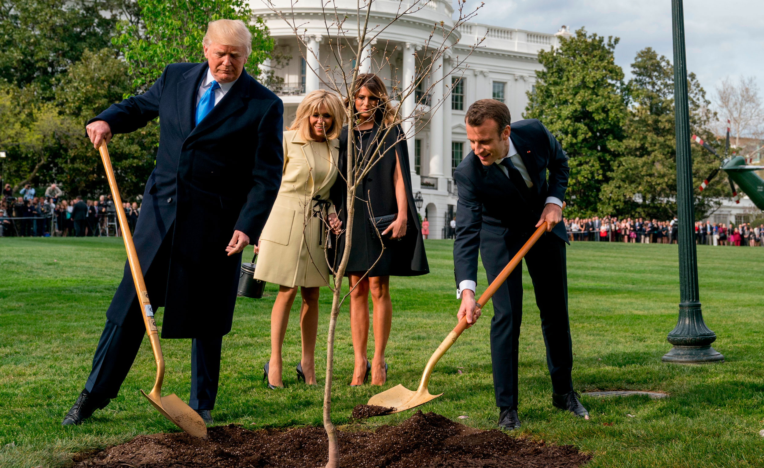 In this April 23, 2018, file photo, US President Donald Trump (left) and French President Emmanuel Macron (right), with Brigitte Macron and Melania Trump (second and third from left, respectively), plant an oak tree on the South Lawn of the White House in Washington DC. 