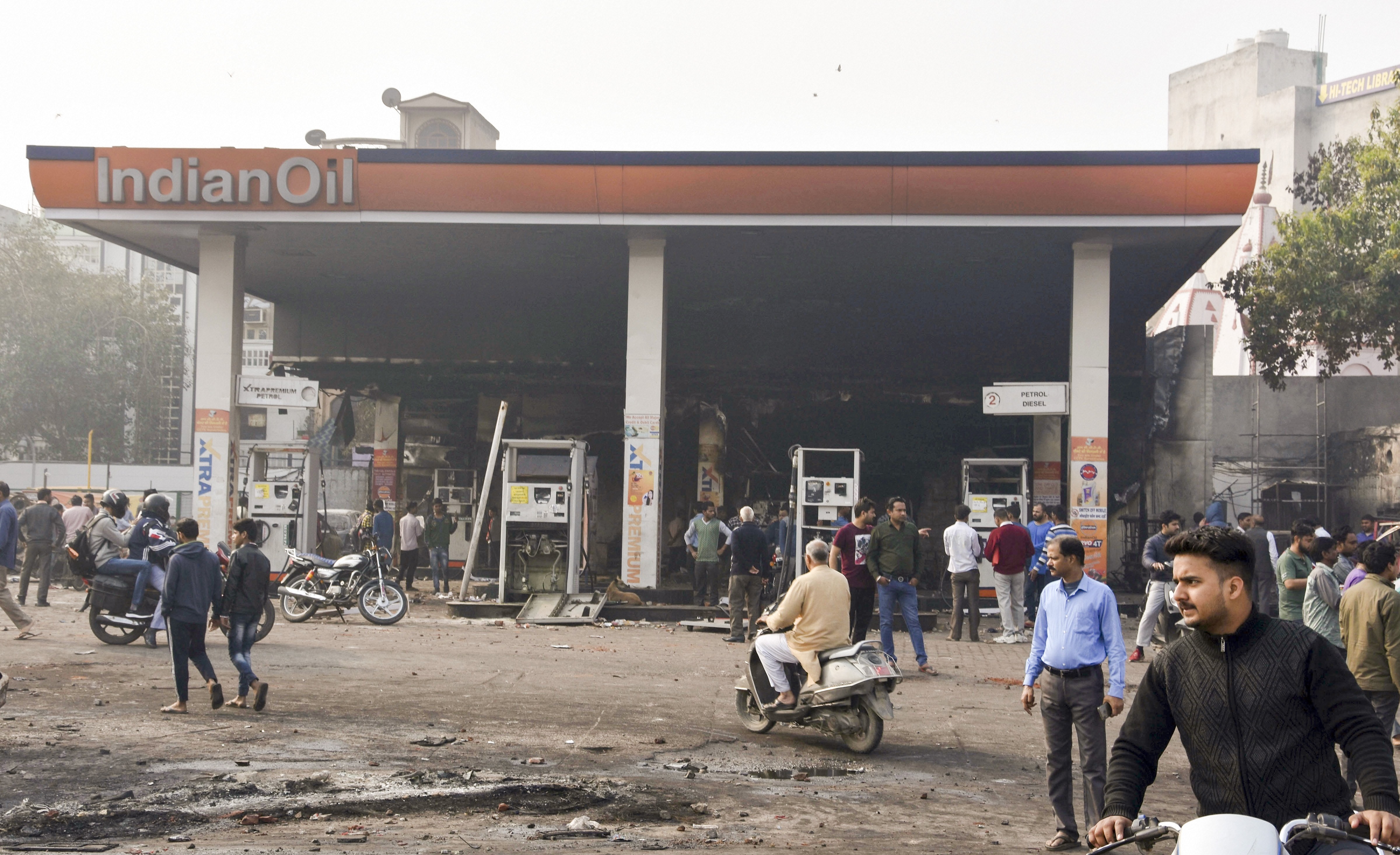 Passersby look at the charred petrol pump which was set ablaze by rioters yesterday during clashes over the new citizenship law, in Bhajanpura area of East Delhi, Tuesday, February 25, 2020