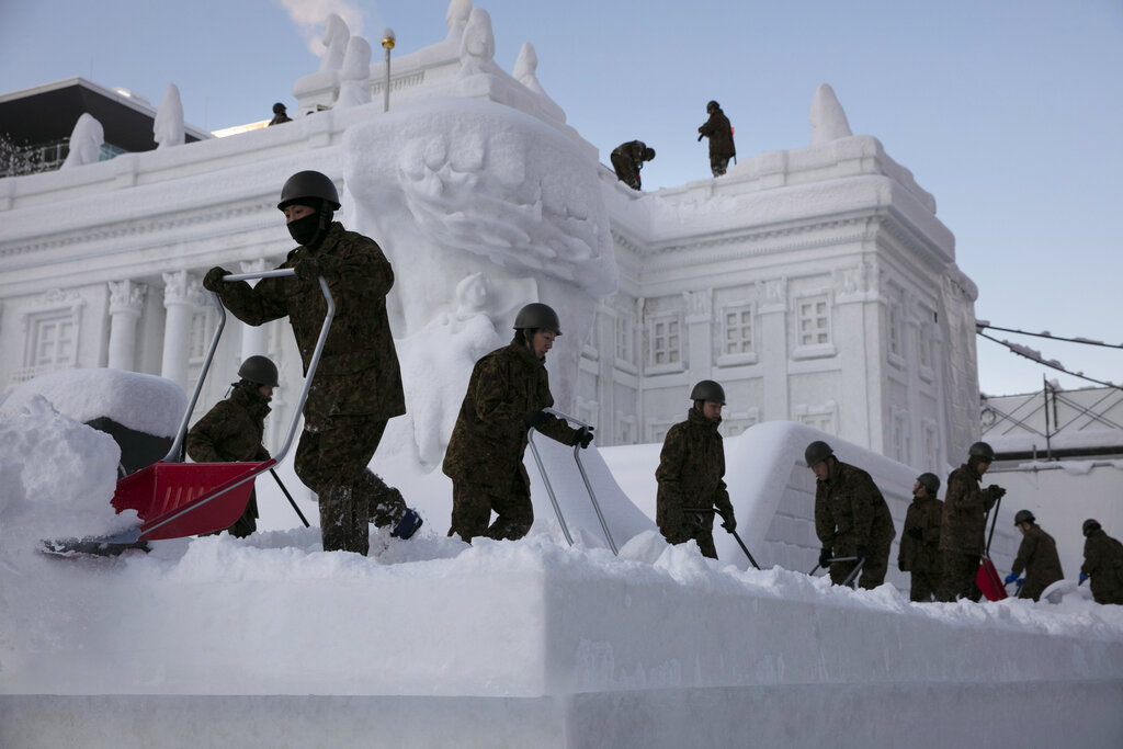 Self-Defense Force members remove fresh snow piled on a large snow sculpture of Poland's Palace on the Isle during the Sapporo Snow Festival at Odori Park in Sapporo