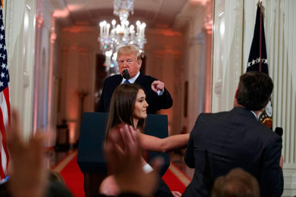 Donald Trump watches as a White House aide reaches to take away a microphone from Jim Acosta during a news conference on Wednesday. 