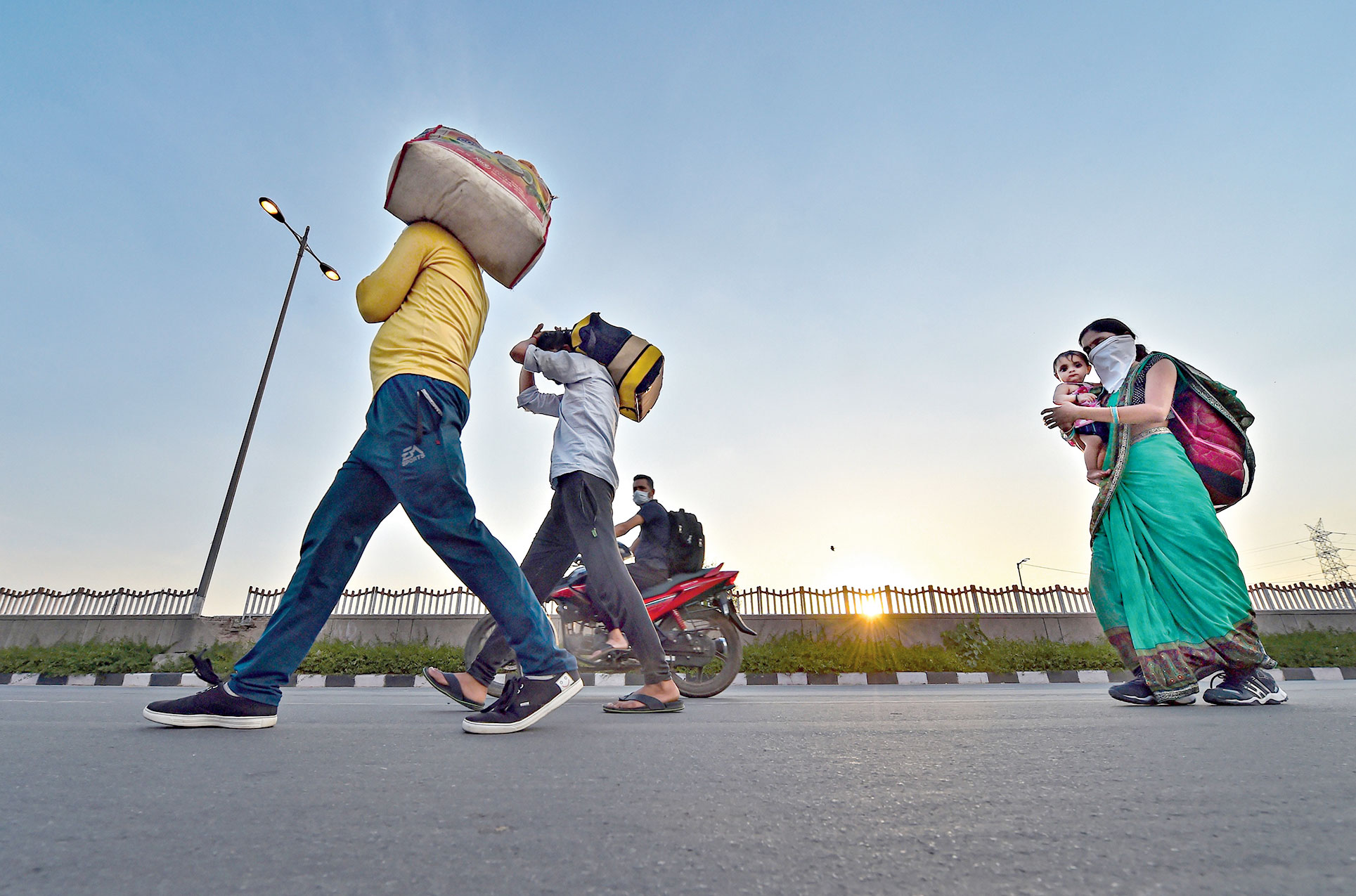 Migrant workers along with their family members walk along the Delhi-UP border road in Delhi on Tuesday. 
