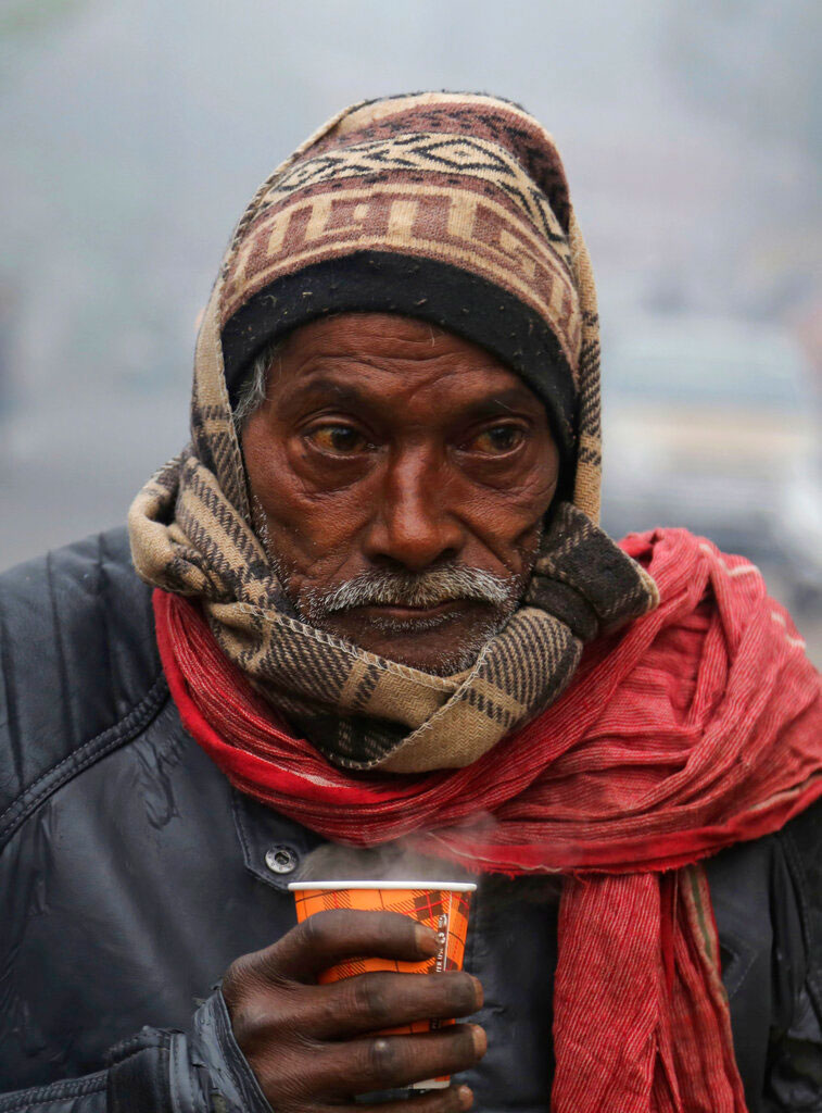 A man holds a hot cup of tea on a cold and foggy morning in Jammu on December 31, 2019.