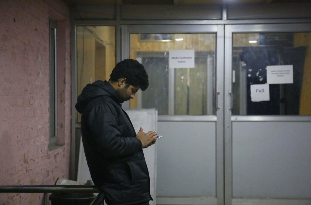 A man checks his cellphone outside a media facilitation centre in Srinagar