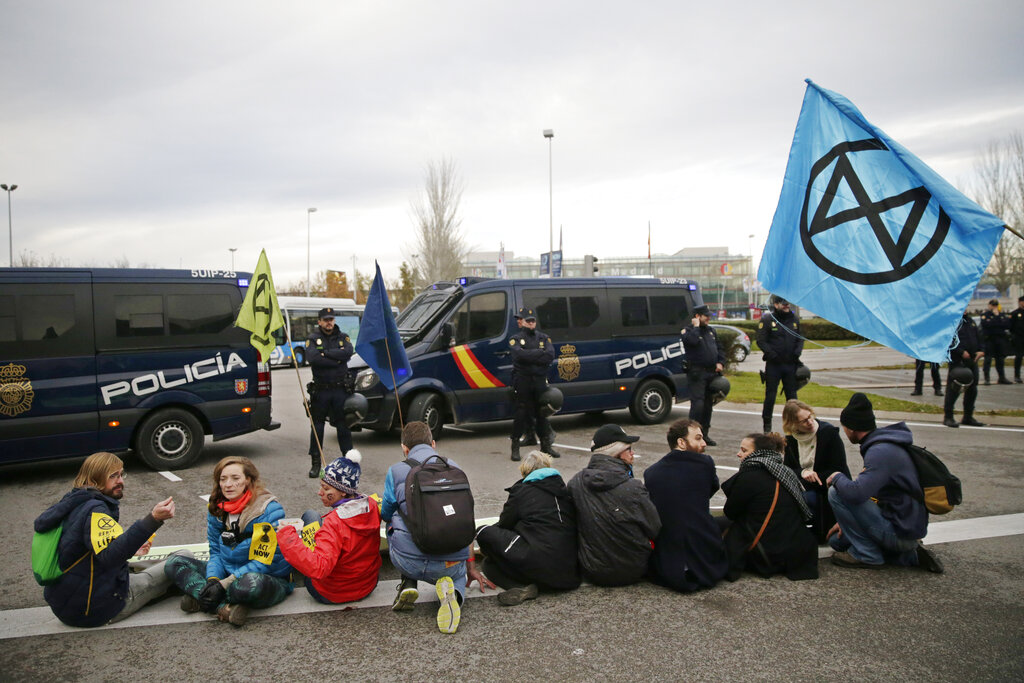 Police watch as activists from the international group called Extinction Rebellion sit blocking the street during a protest against climate change outside the COP25 Climate summit in Madrid, Spain, Monday, Dec. 9, 2019.