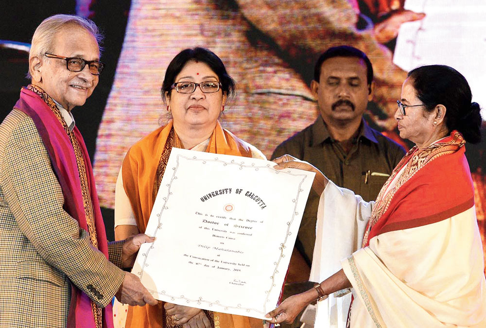 Paediatrician Dilip Mahalanabis receives an honorary DSc from chief minister Mamata Banerjee at Calcutta University’s convocation on Monday. Also in the picture is CU vice-chancellor Sonali Chakravarti Banerjee.

