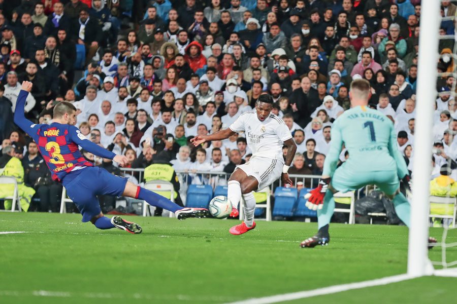 Vinicius Junior scores Real Madrid’s opening goal past Barcelona goalkeeper Marc-Andre ter Stegen (right) as Gerard Pique tries to block at the Bernabeu on Sunday. 