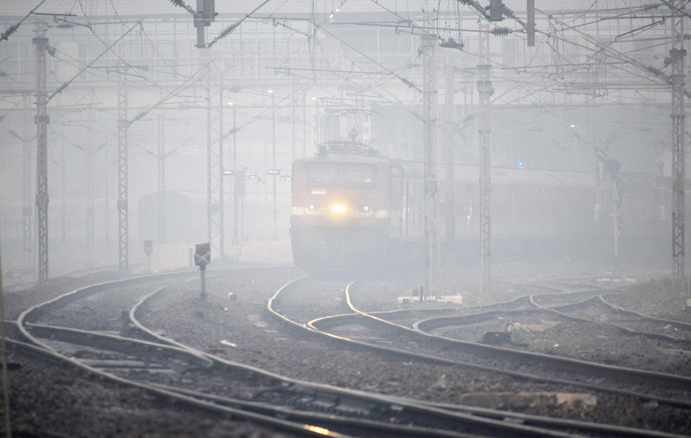 A train slows down as fog envelopes railway tracks on a cold morning in Allahabad on December 12