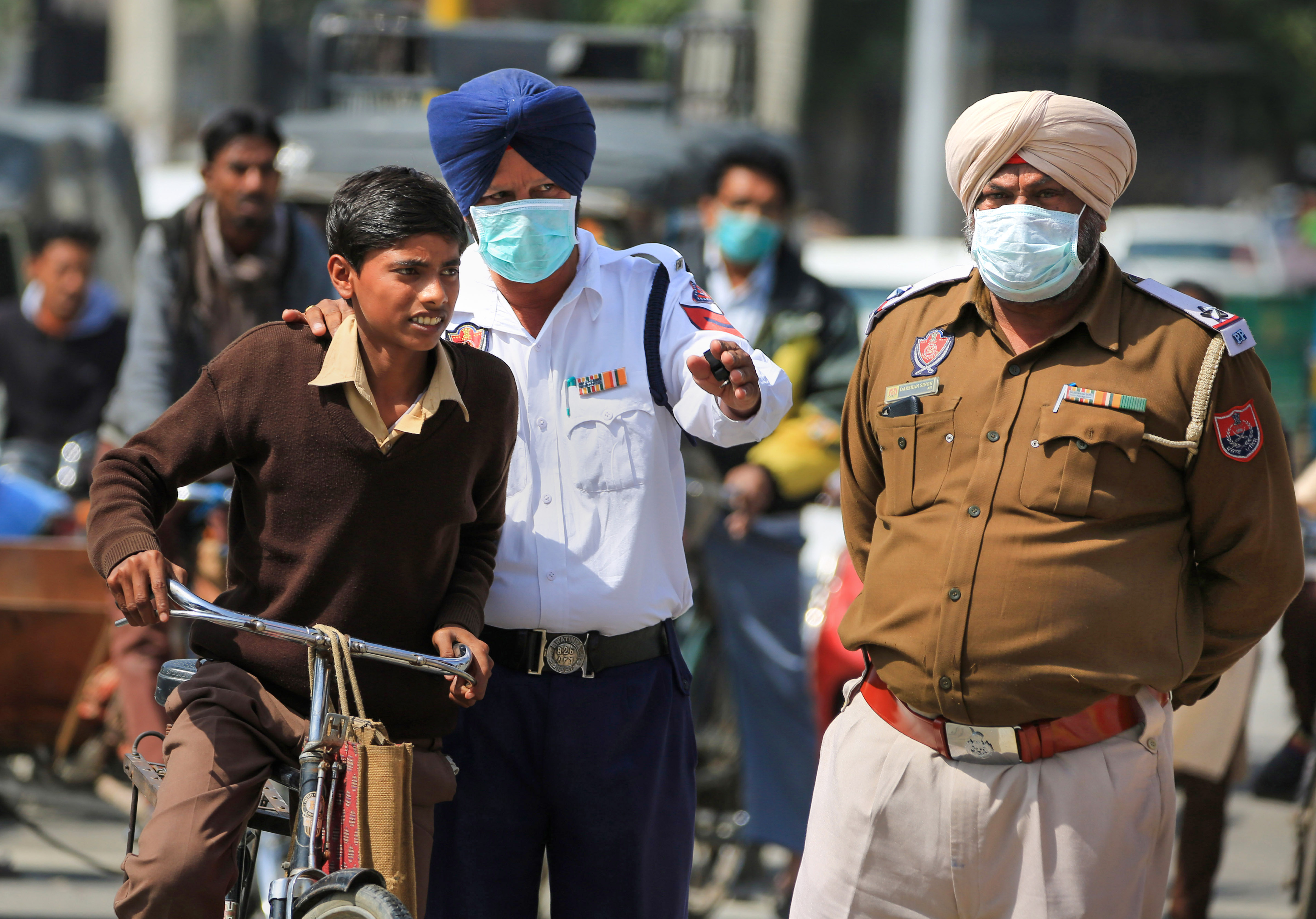 Punjab police personnel wearing protective masks in the wake of the novel coronavirus scare (COVID-19) guide a commuter in Bathinda, Friday, March 13, 2020.