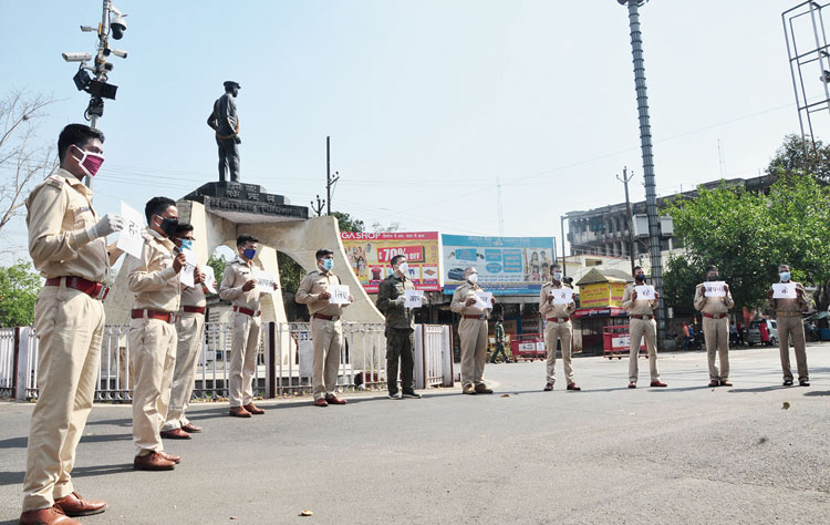 Police personnel hold placards asking residents to stay indoor at Randhir Verma Chowk in Dhanbad on Thursday. 