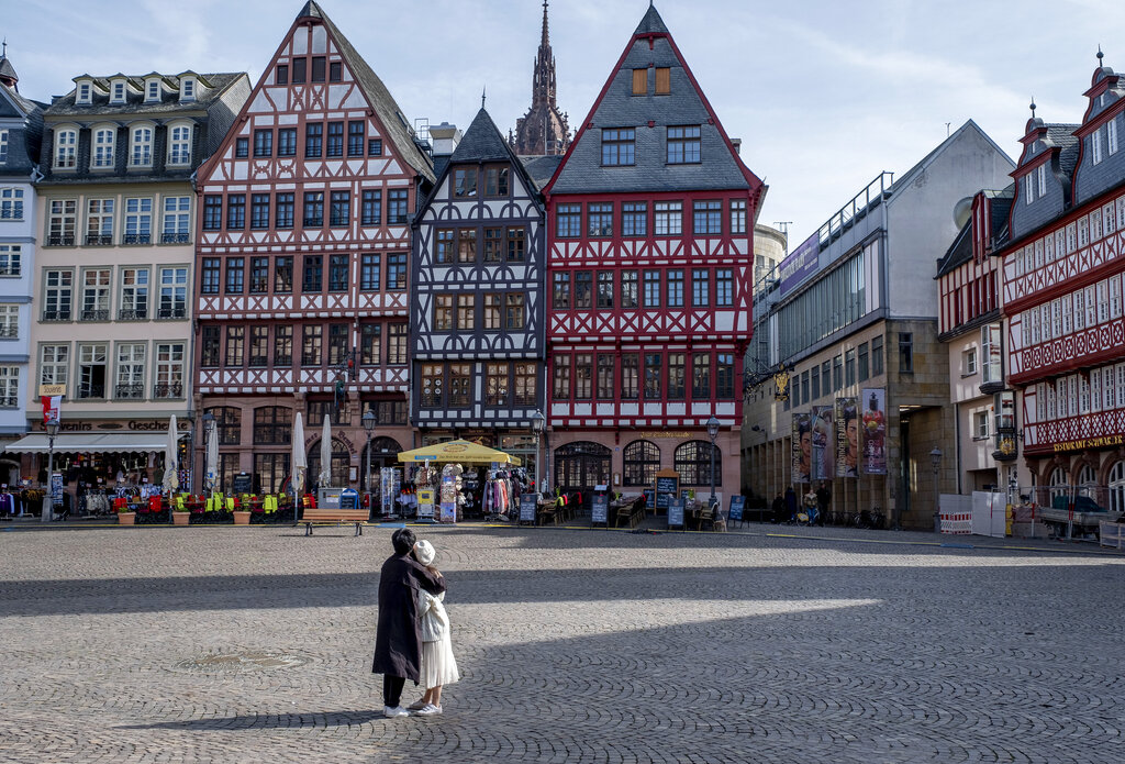 An Asian couple looks at timberframe houses at the almost empty Roemerberg square, the main tourist spot in Frankfurt, Germany, Sunday, March 15, 2020. Only for most people, the new coronavirus causes only mild or moderate symptoms, such as fever and cough. For some, especially older adults and people with existing health problems, it can cause more severe illness, including pneumonia.