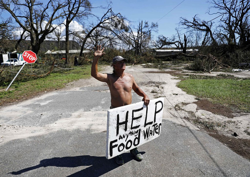 A man looks for food and water as downed trees prevent him from driving out of his damaged home with his family in the aftermath of Hurricane Michael in Springfield, Florida.