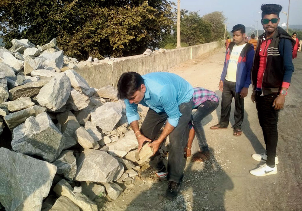 Heavy duty: Social workers remove boulders from the road over Maithon Dam on Tuesday. 
