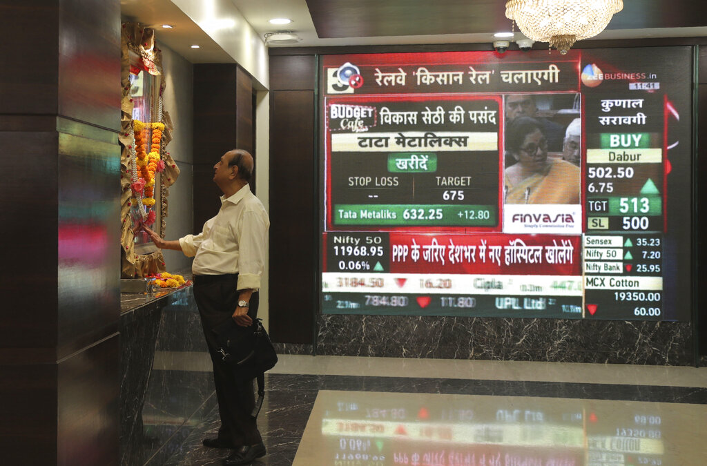 A man offers prayers to a Hindu goddess at the Bombay Stock Exchange (BSE) office, as Finance Minister Nirmala Sitharaman is seen on a television screen presenting the annual budget in Mumbai