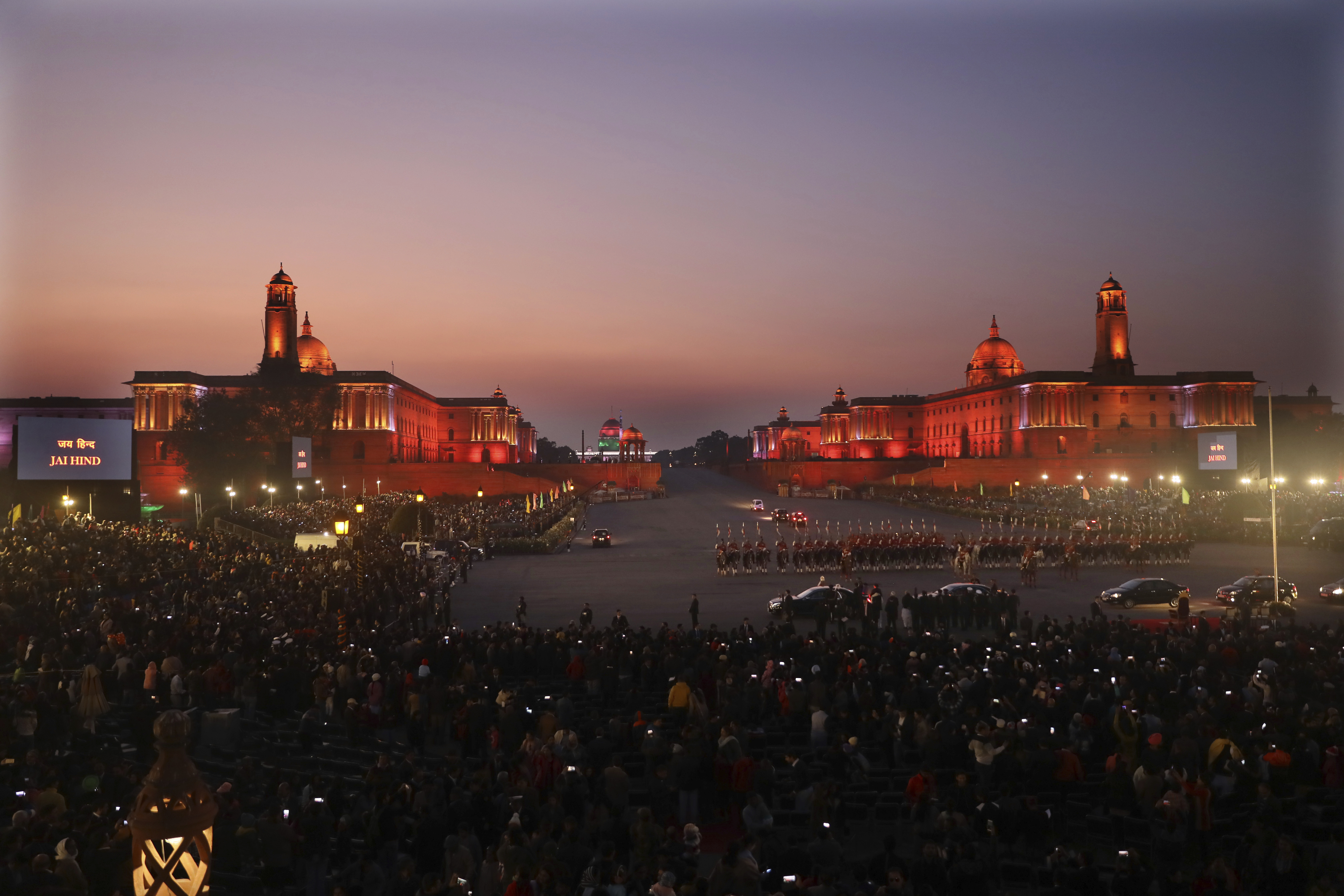 Members of the crowd hold up their mobile phones to take pictures of the illuminated Indian Presidential Palace, center, and the north and south blocks, the government seat of power, as the president leaves at the end of the Beating Retreat ceremony at Raisina hills, in New Delhi, India, Wednesday