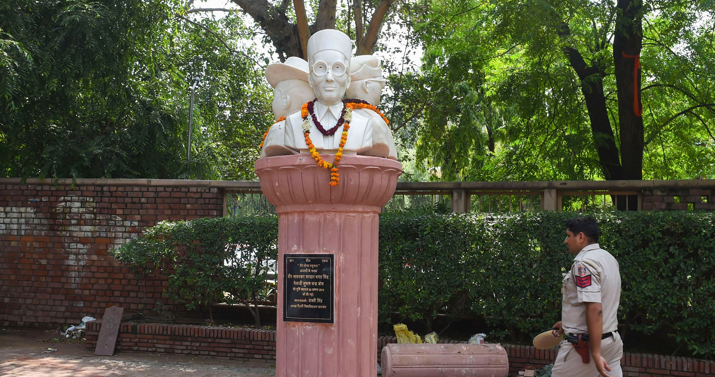 A policeman walks past the busts of Veer Savarkar, Subhash Chandra Bose and Bhagat Singh installed outside the Arts Faculty of Delhi University, in New Delhi, on August 21, 2019. 