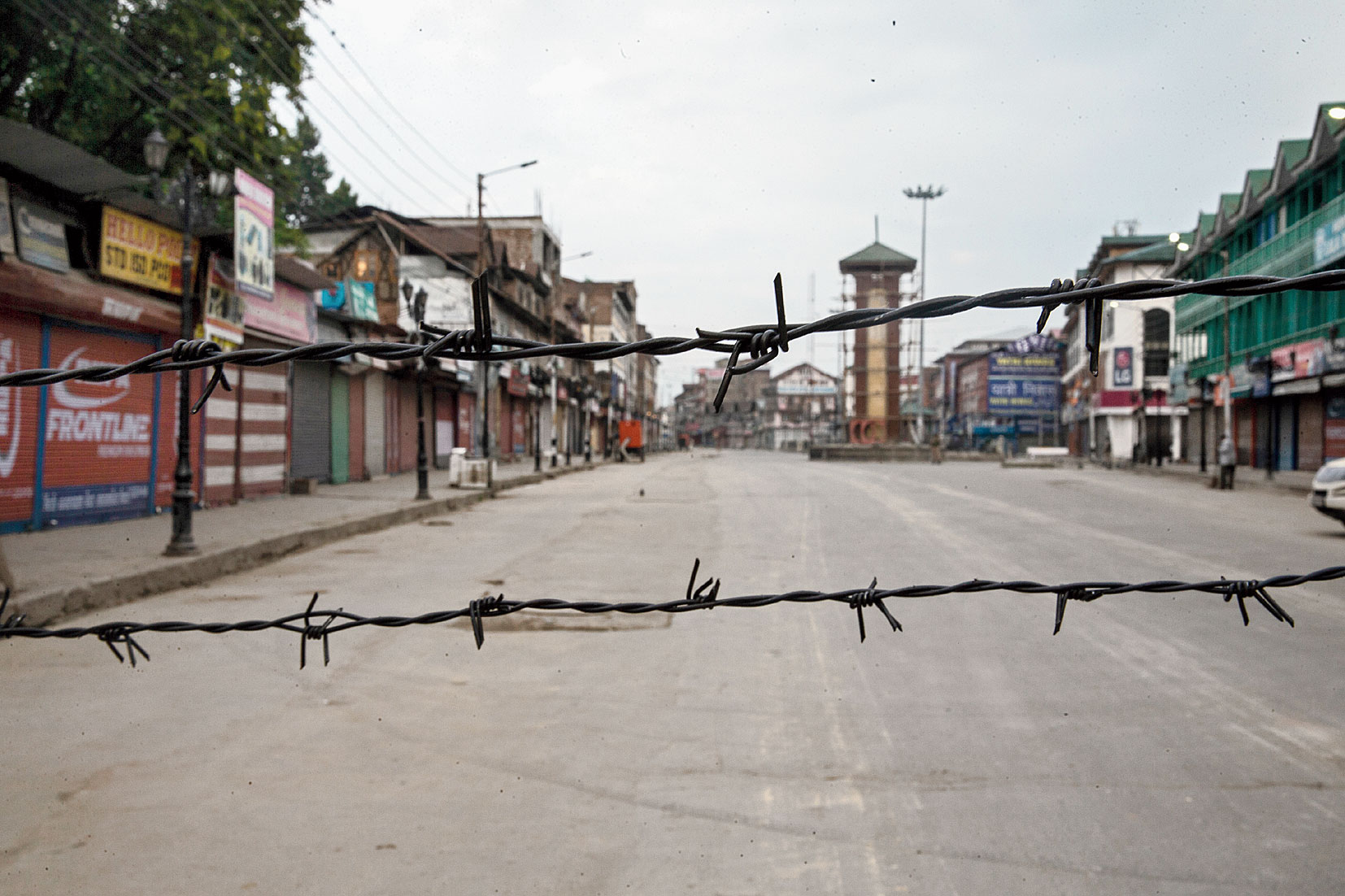 A deserted street is seen through barbwire that was strung as a blockade during curfew in Srinagar on August 6, 2019.