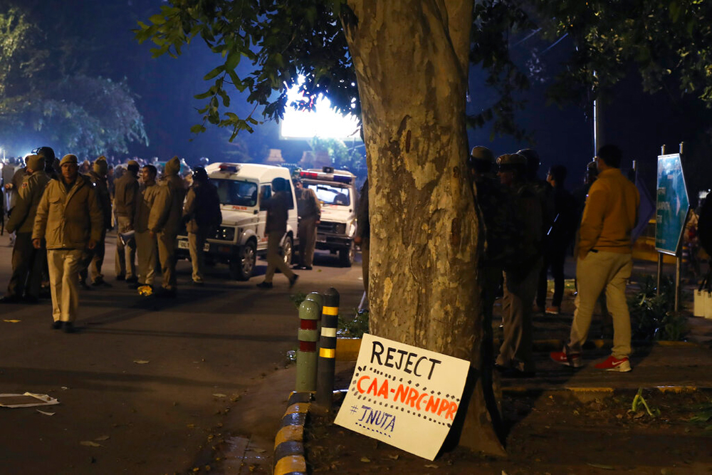 A placard rests against the trunk of a tree after police caned protesting students in New Delhi on Thursday