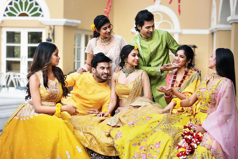 A lot of bright and warm hues, with minimal as well as heavy embroidery, set a happy lookbook for the Haldi ceremony. (L-R) Meghna’s lehnga in bright yellow designed with resham booti is minimal yet gorgeous. Roop in a yellow Benarasi silk kurta designed with knot stitches showcased a dapper look for the groom-to-be. Diti looked vibrant in the sleeveless mustard lehnga embellished with gota work and Swarovski stones. Shrimoyee showed how to keep it traditional and beautiful in a yellow resham-embroidered sari. Hiya’s raw silk lehnga with heavy resham embroidery in multicoloured thread is perfect for the bride who wants to dress up colourful. Shadman’s green Benarasi silk panjabi with hand embroidery is for the groom’s friend. Aditi’s pastel pink net lehnga with multicoloured sequins hand-work is for the subtle fashion lover. “Haldi is all about yellow and mustard,” said Anand.