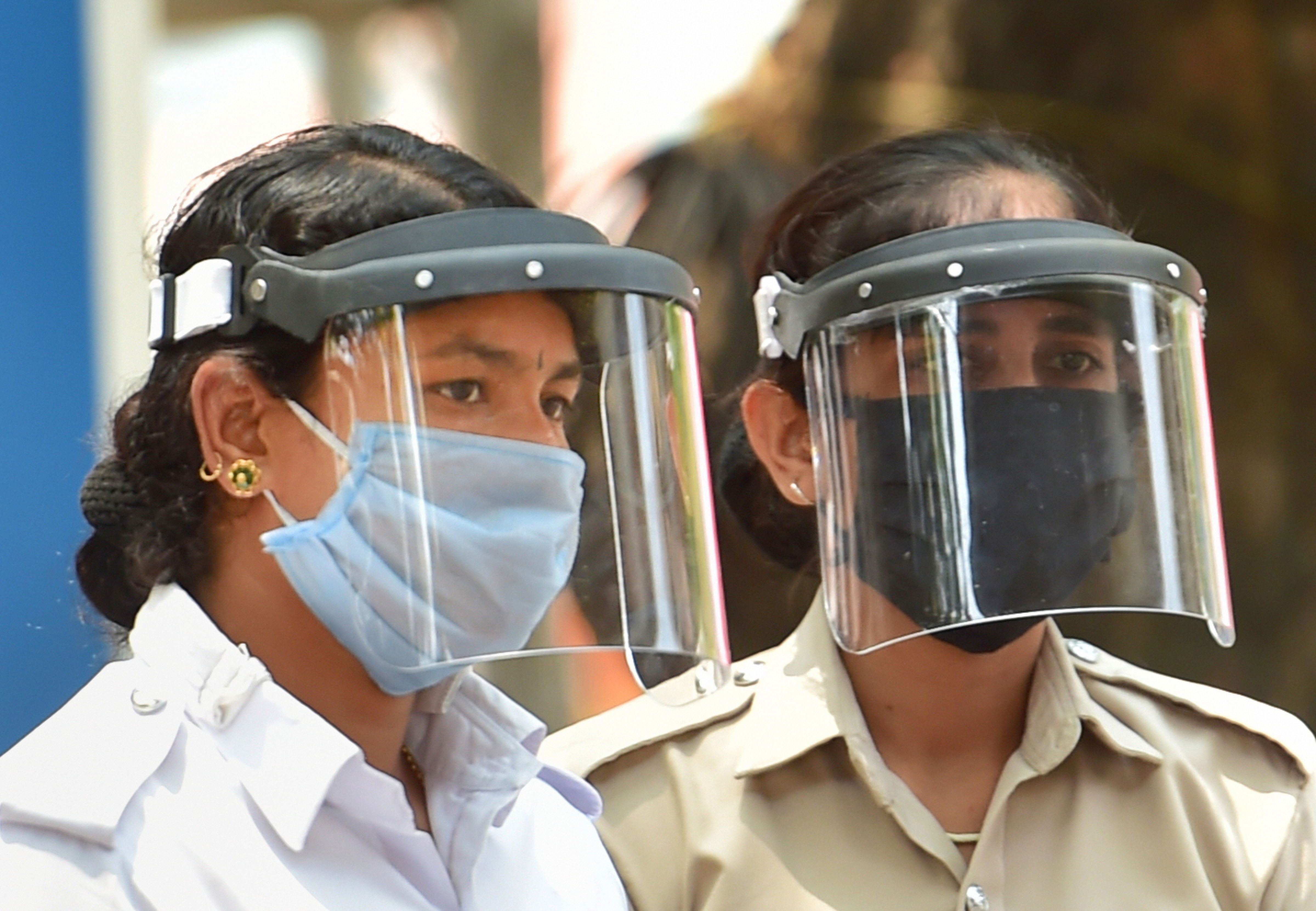 Policewomen wearing visors perform their duty during the nationwide lockdown in the wake of coronavirus pandemic, in Bengaluru, Saturday, April 11, 2020