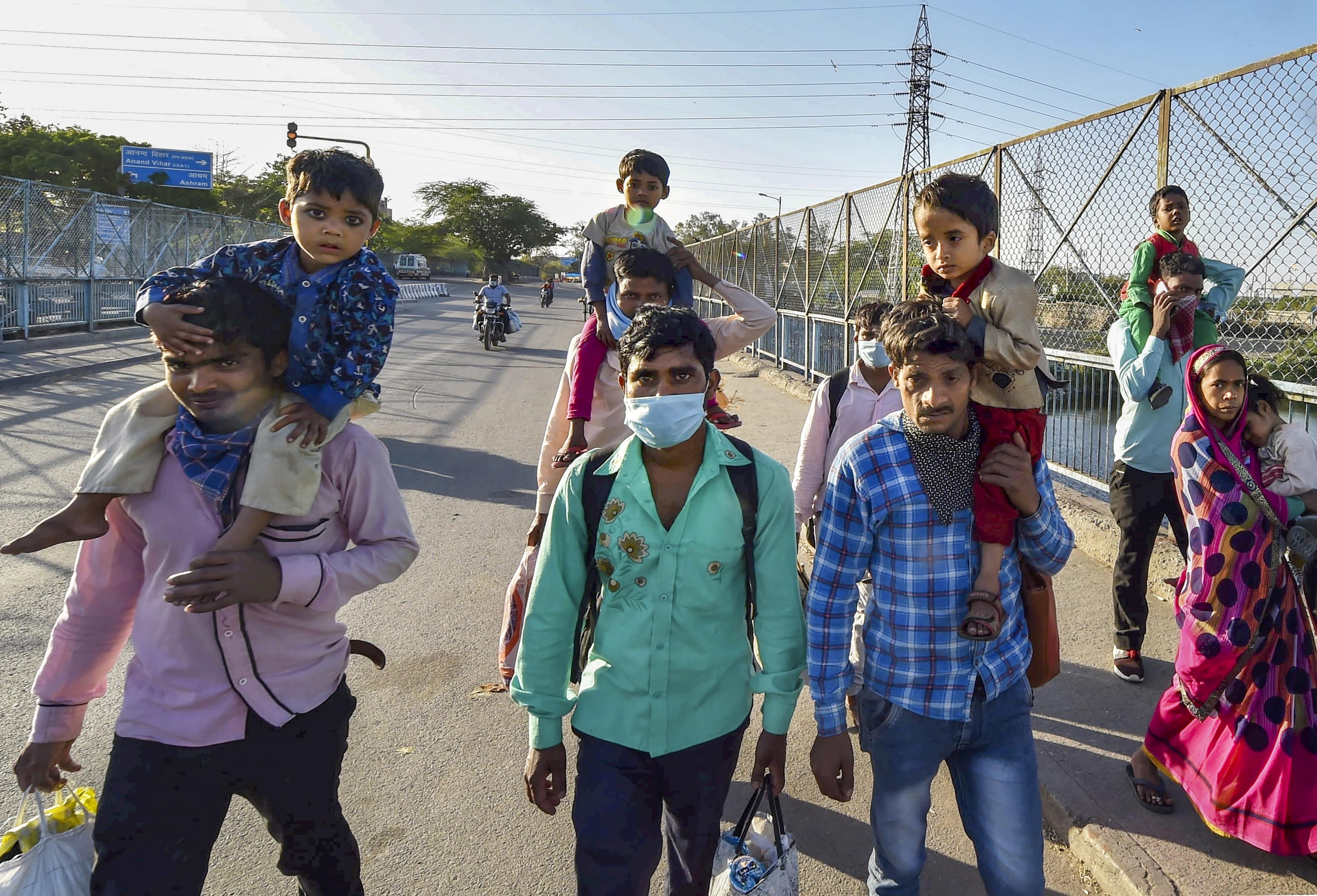 Migrant workers with their family members walks to their native village during a nationwide lockdown, imposed in the wake of coronavirus pandemic, at Kalyanpuri in East Delhi, Sunday, March 29, 2020.