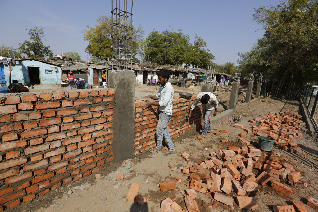 Workers construct a wall in front of a slum ahead of U.S. president Donald Trump's visit, in Ahmedabad
