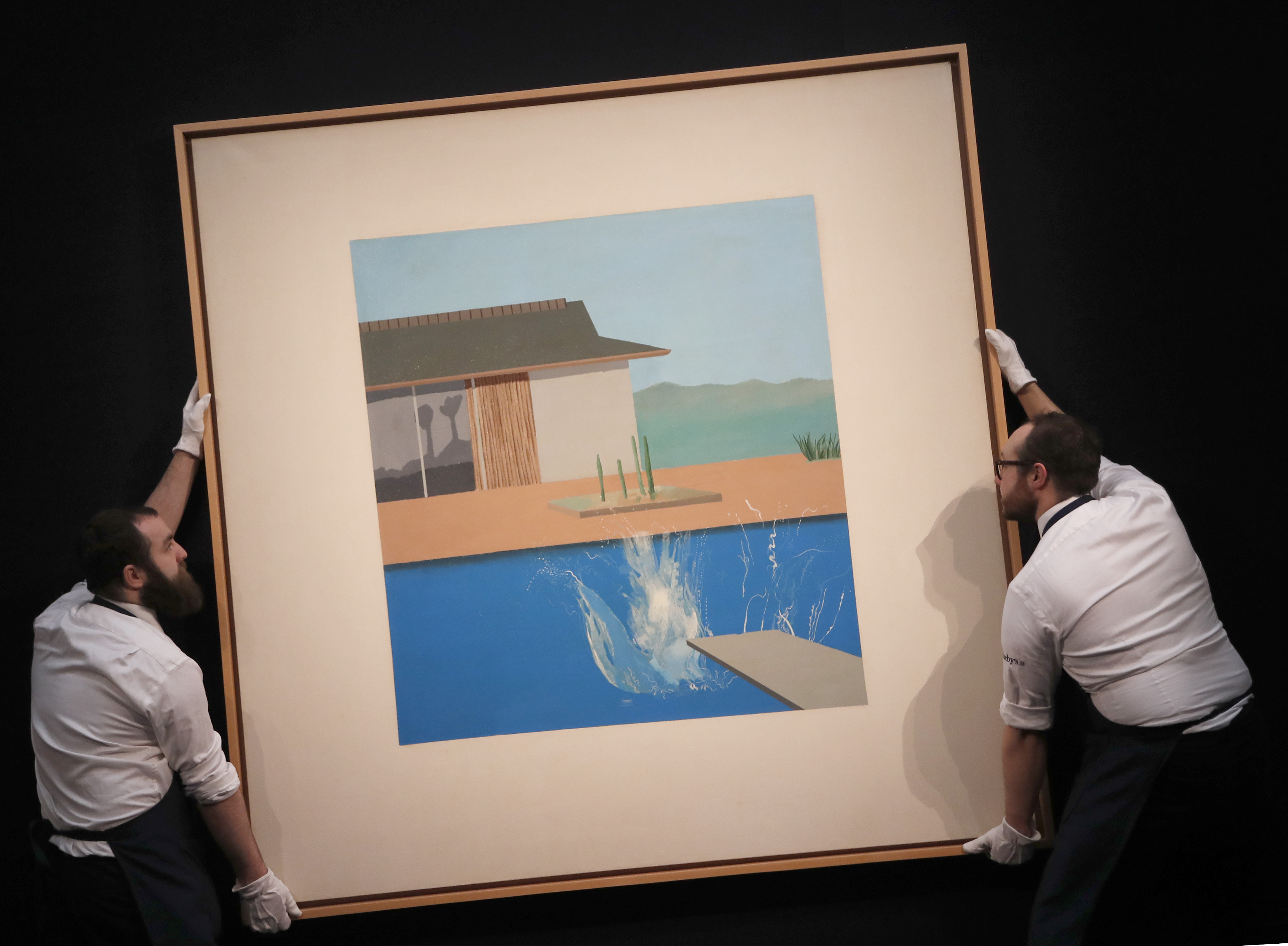 Two Sotheby's employees adjust David Hockney's painting 'The Splash' at Sotheby's contemporary Art sale preview in London on Friday