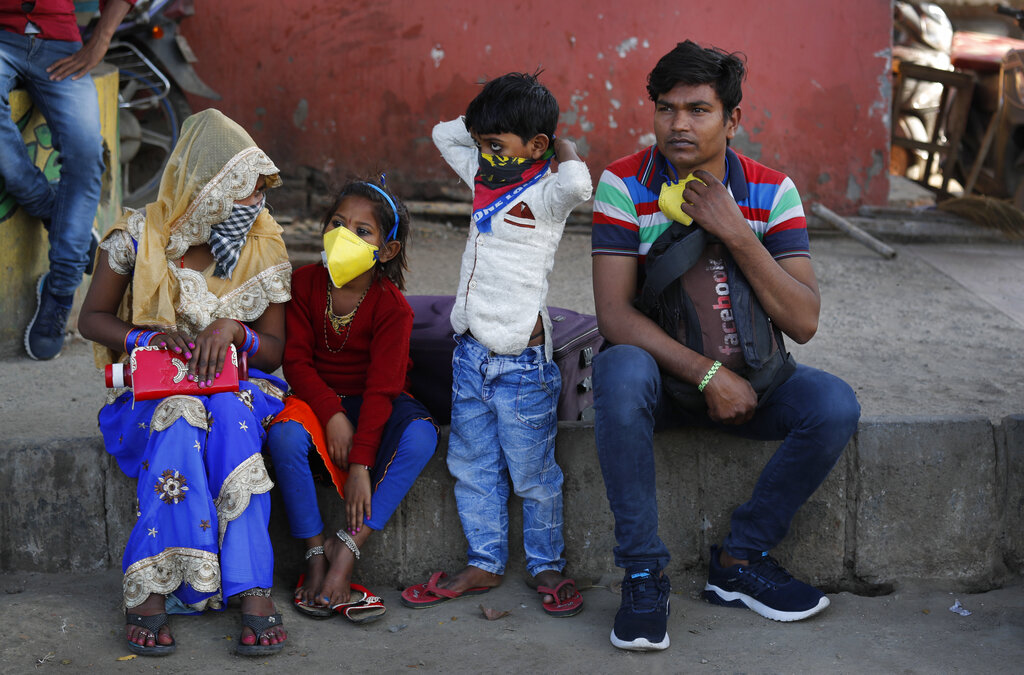 Migrant daily wage laborer Ram Bhajan Nisar and his family wait for transportation to travel to their hometown following a lockdown amid concern over spread of coronavirus in New Delhi, on Friday, March 27, 2020.