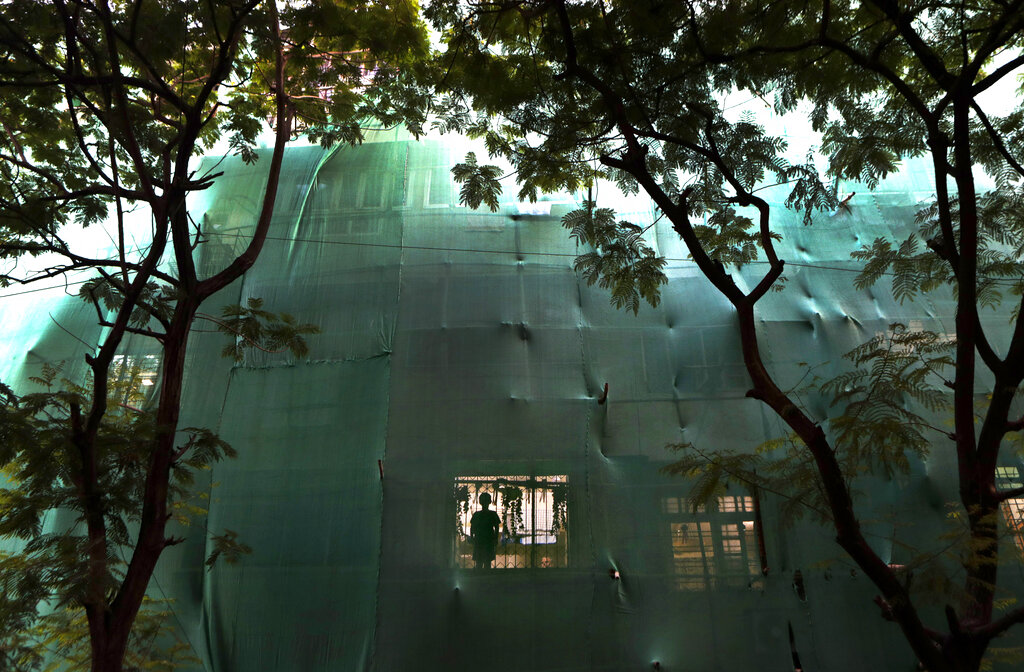 A boy looks out from the window of his house of a residential building which is covered with a green cloth for outside repairing during the coronavirus pandemic lockdown in Mumbai, on Monday