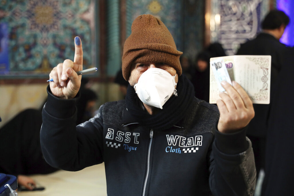 A voter shows his identification and inked finger while voting for the parliamentary elections at a polling station in Tehran