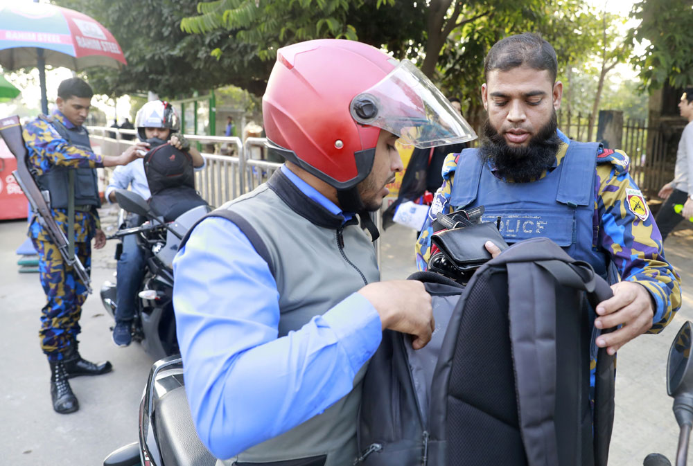 Bangladeshi policemen check the bags of commuters in Dhaka on December 24, 2018. Bangladesh police have arrested more than 10,500 Opposition activists in a crackdown ahead of the elections, Opposition parties said.
