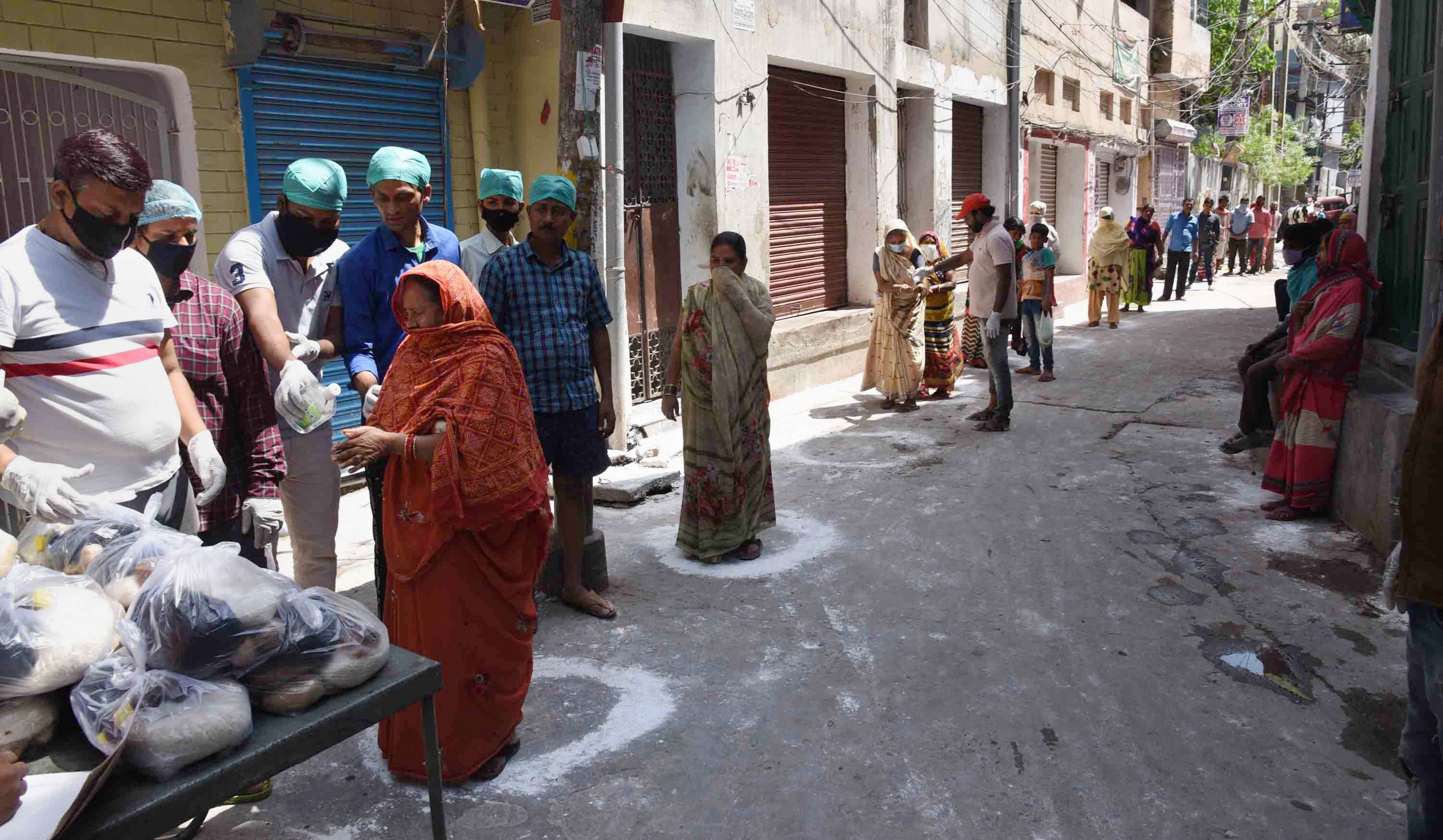 People stand in painted circles to maintain safe distance and collect essential food items during the nationwide lockdown imposed in the wake of coronavirus pandemic, in Patna, Tuesday, April 7, 2020