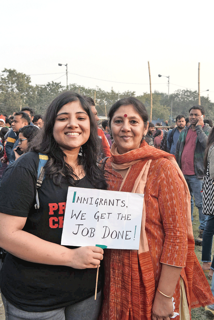 Sukanya Sanyal, who teaches English at Vivekananda College in Thakurpukur, with (left) daughter Proma, a former student of history at the erstwhile Presidency College. Proma’s poster reads a famous line from a song on the Hamilton Mixtape, an album featuring covers and remixes of songs from Hamilton, the record-breaking musical about how America’s identity was shaped by an immigrant, Alexander Hamilton. “Immigrants are hard-working and help in nation building,” said Proma.