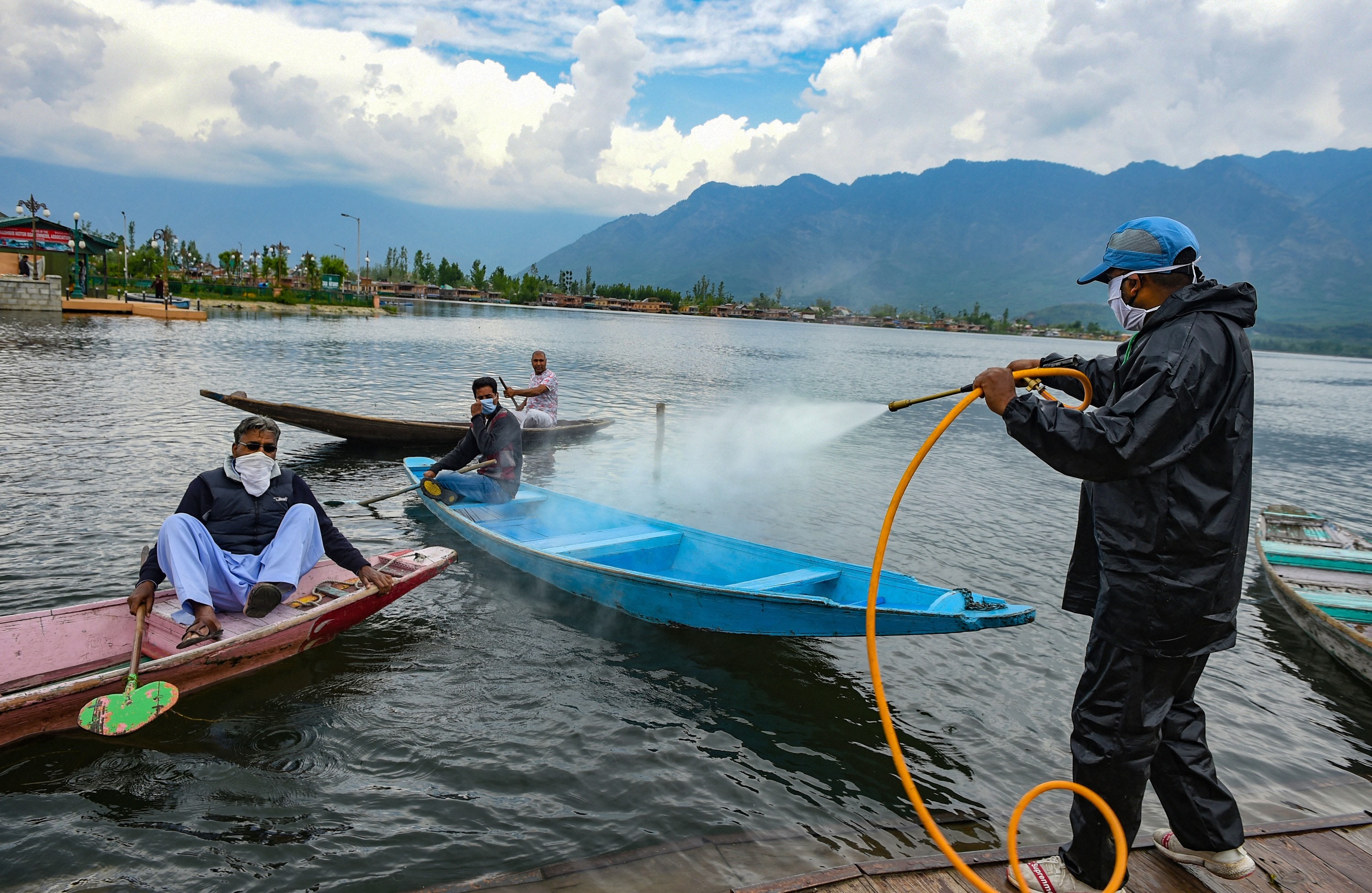 A worker sprays disinfectant on boats anchored along Dal Lake near Nehru Park during the nationwide lockdown to contain the spread of coronavirus, in Srinagar, Monday, May 4, 2020.