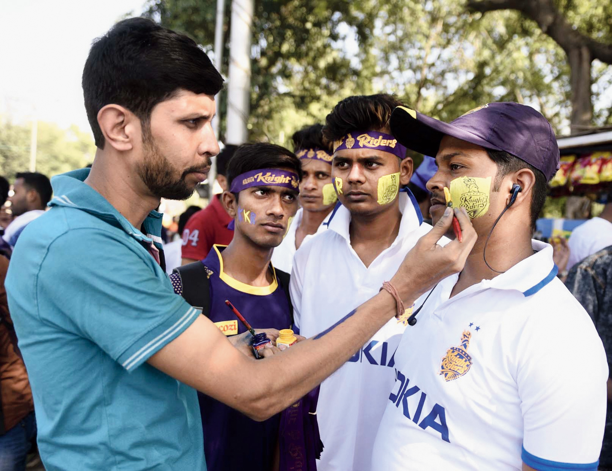 KKR fans get their faces painted in their team colours outside Eden.
