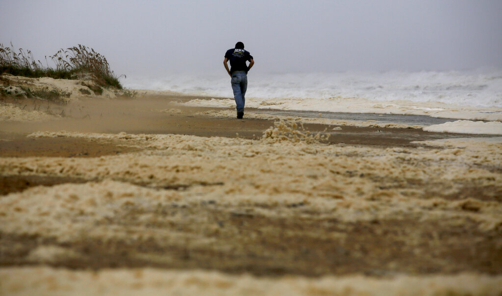A man walks down the beach as Hurricane Dorian passes through Virginia Beach, Va., on Friday, Sept. 6, 2019.